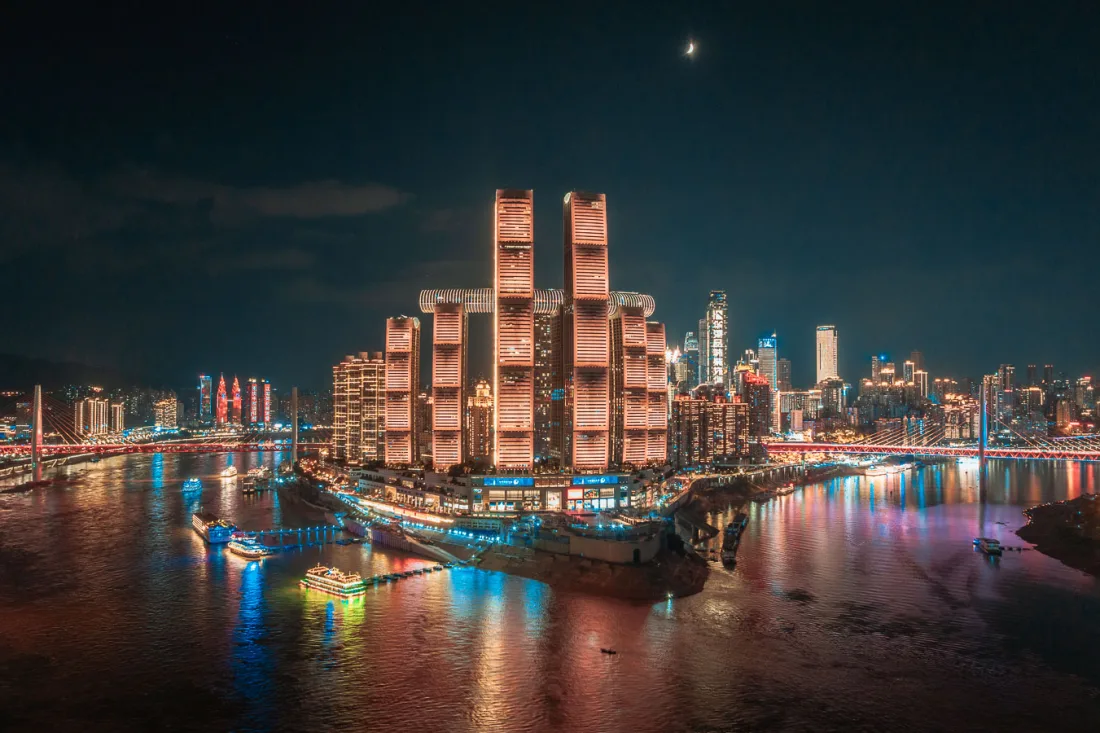 Raffles City and the illuminated Chongqing skyline seen from Chaotianmen Plaza at night