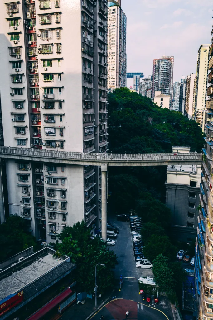 Trees and a city street visible far below an elevated Chongqing walkway