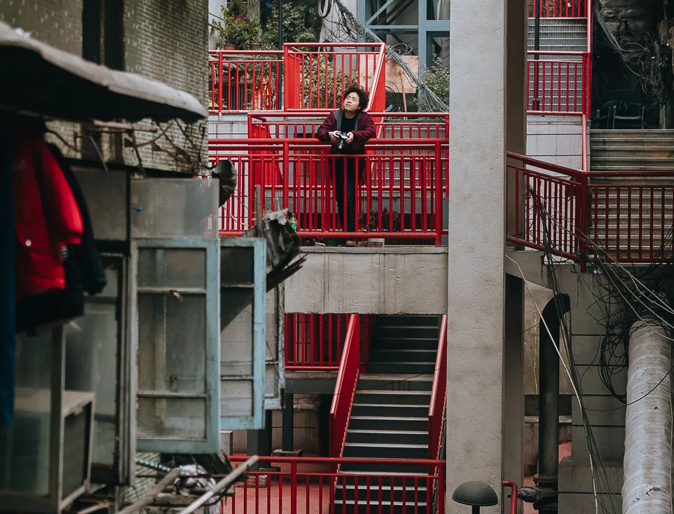 Jackson standing on a red elevated walkway in a Chongqing residential neighbourhood