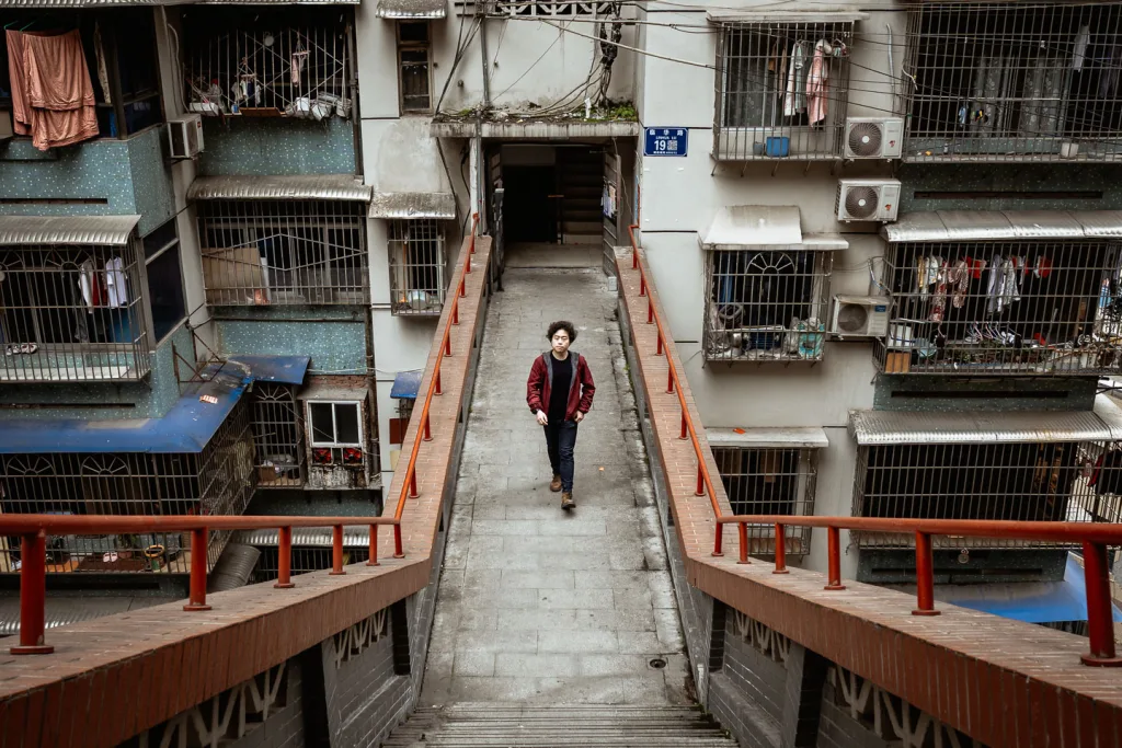 Jackson walking through the layered passages of a Chongqing residential complex