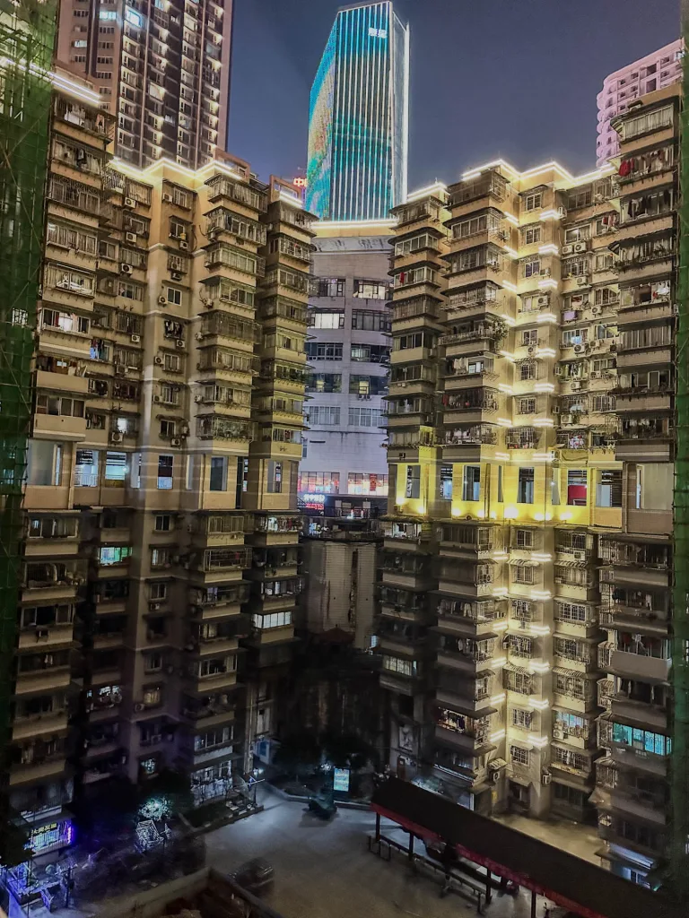 The illuminated inner courtyard of a dense Chongqing apartment complex