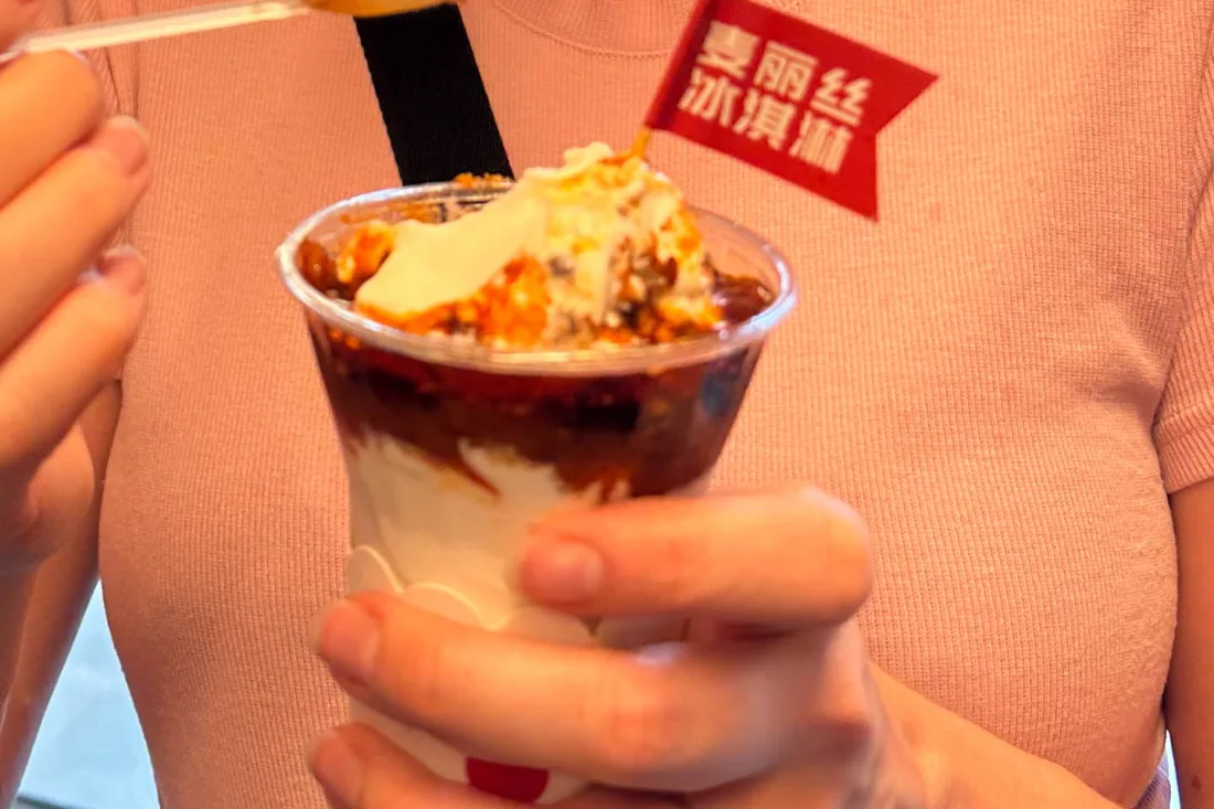 A traveller holding a cup of spicy Chongqing street food