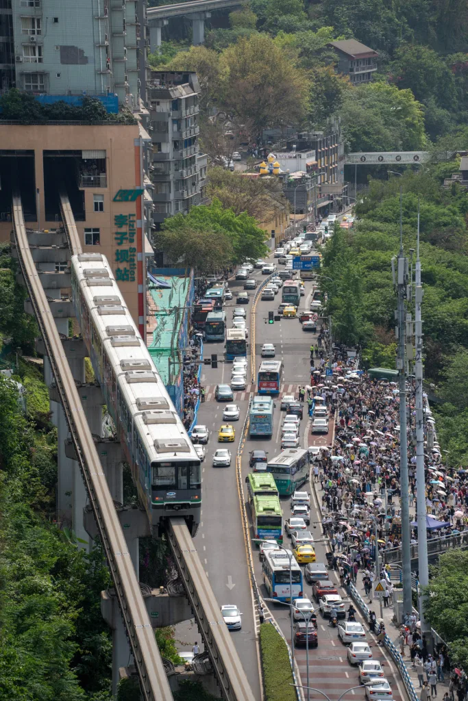 A busy road descending between steep Chongqing hills and buildings