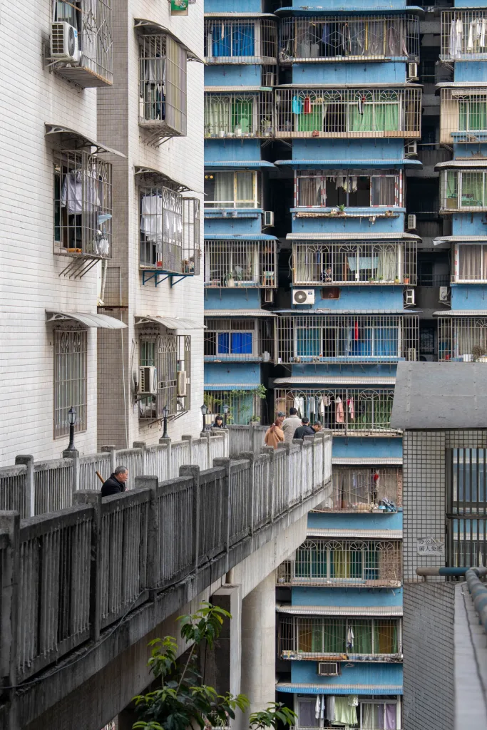 A narrow elevated passage leading between colourful Chongqing apartment blocks