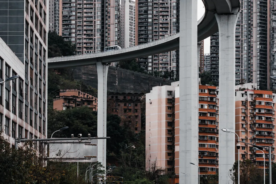 A white car photographed among Chongqing's elevated roads and modern city architecture