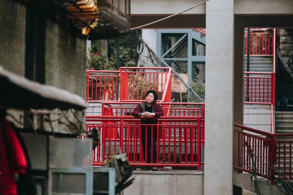 A portrait among the red walkways of a layered Chongqing residential neighbourhood