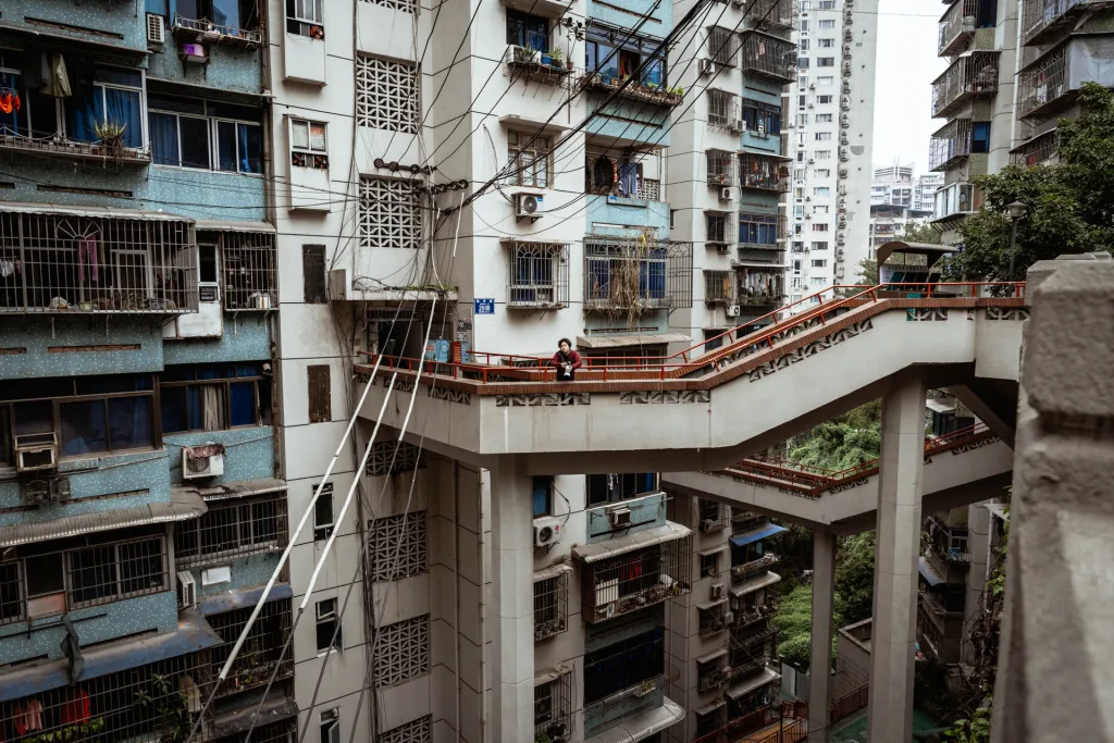 A portrait among the red walkways of a layered Chongqing residential neighbourhood