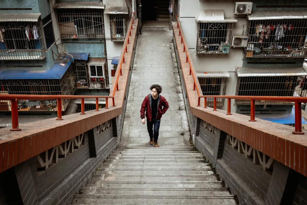 A portrait among the red walkways of a layered Chongqing residential neighbourhood