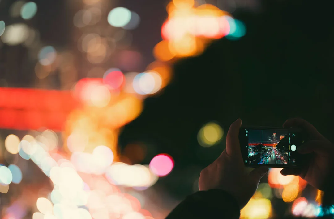 A phone capturing Chongqing's blurred riverfront lights at night