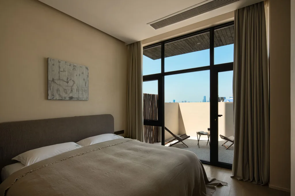 Warm minimalist guest room opening onto a private rooftop terrace