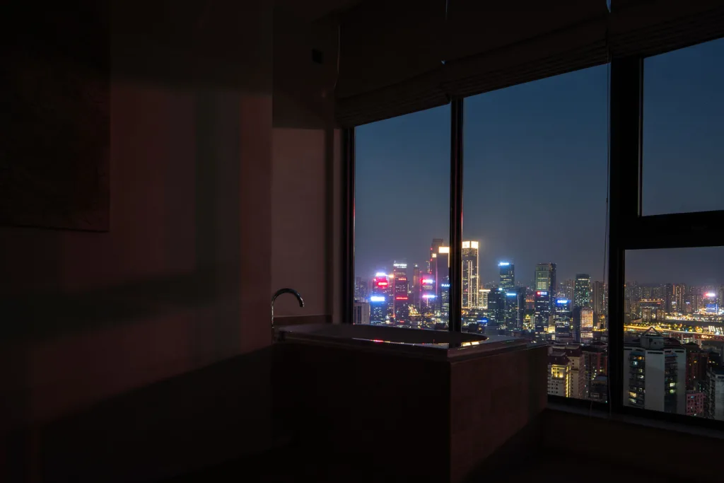 Night skyline seen from a guest room bath at SOMMET Rooftop Hotel