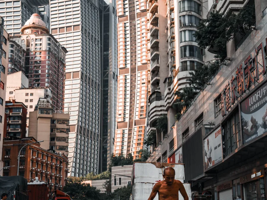 A porter walking through Gangyu Plaza between historic and modern Chongqing buildings